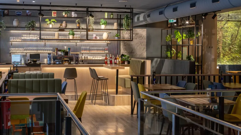 Bar mit beleuchteten Regalen, Pflanzen und Sitzbereich im Restaurant CHILLY in St. Johann im Pongau