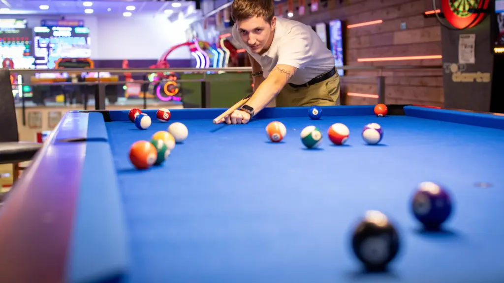 Junger Mann zielt konzentriert mit dem Queue beim Billard im Restaurant CHILLY in St. Johann im Pongau
