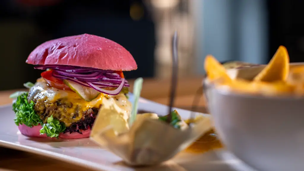 Cheeseburger mit pinkem Brötchen, geschmolzenem Käse, Salat, Tomate und roten Zwiebeln im Restaurant CHILLY in St. Johann im Pongau