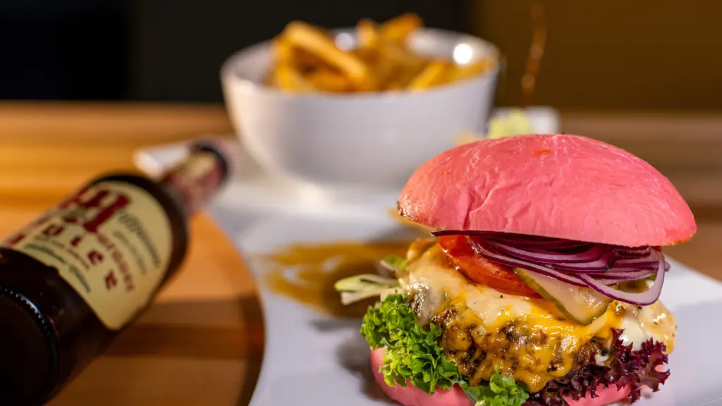 Cheeseburger mit pinkem Brötchen und geschmolzenem Käse in Nahaufnahme, mit Pommes und Murauer Bier im Restaurant CHILLY in St. Johann im Pongau