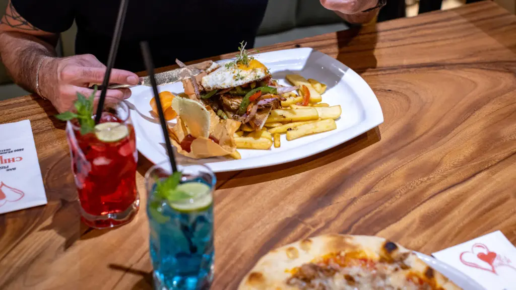 Gericht mit Fleisch, Paprika, Spiegelei und Pommes, dazu bunte Cocktails auf dem Tisch im Restaurant CHILLY in St. Johann im Pongau
