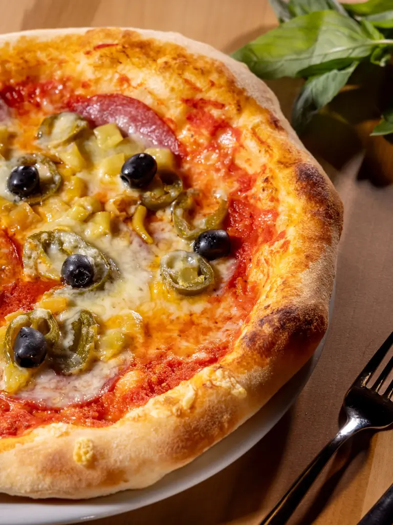 Pizza Diavolo mit Salami, Pfefferoni und Oliven in Nahaufnahme im Restaurant Chilly in St. Johann im Pongau