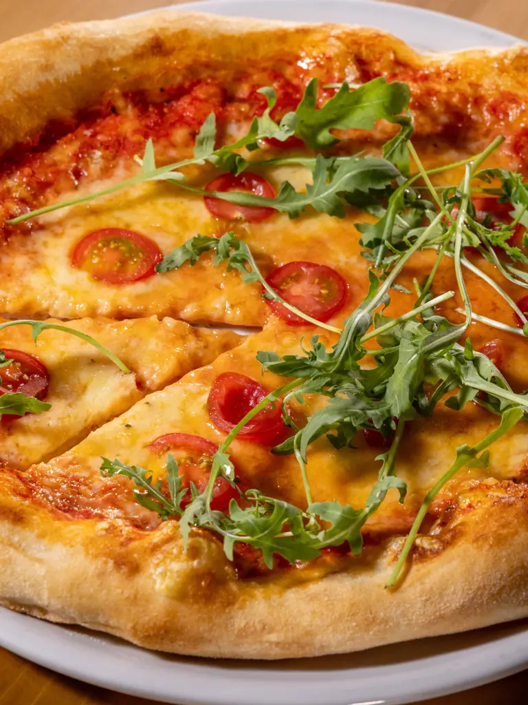 Pizza mit Kirschtomaten, Mozzarella und frischem Rucola in Nahaufnahme im Restaurant Chilly in St. Johann im Pongau