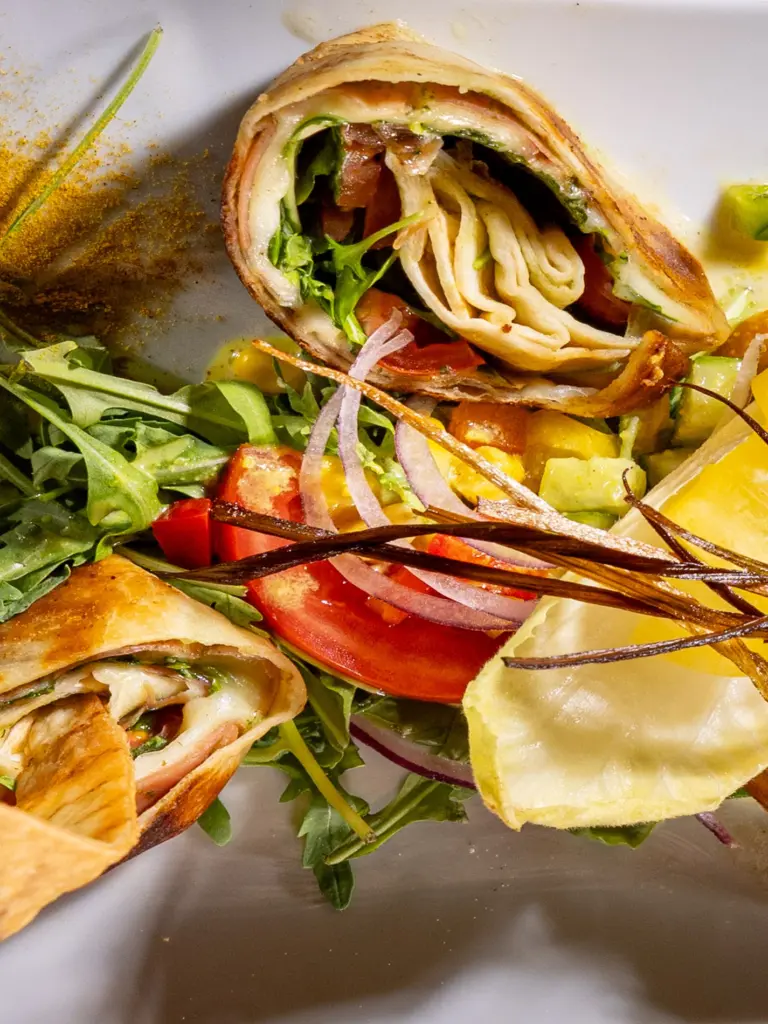 Aufgeschnittener Wrap mit Schinken, Käse und Rucola auf Salatbett im Restaurant Chilly in St. Johann im Pongau